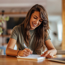 Woman smiling while taking notes in office