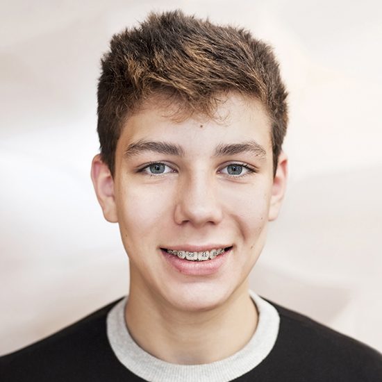 Smiling teen with braces receiving dentofacial orthopedics treatment