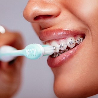 woman brushing teeth with braces