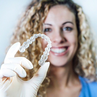 Orthodontist smiling while holding an Invisalign tray