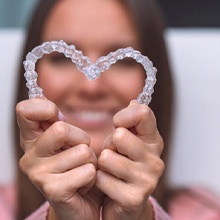 Woman making a heart with her Invisalign aligners