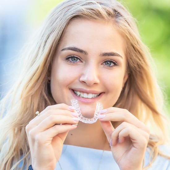 Smiling young woman holding Invisalign tray