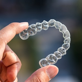 Hand holding an Invisalign tray