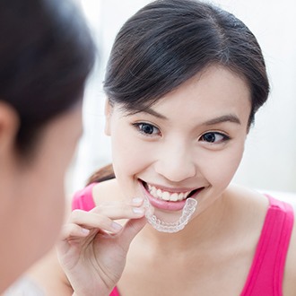 Smiling woman placing her Invisalign tray