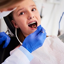 a patient with braces brushing their teeth