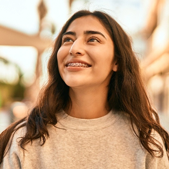 A young female smiling and looking upward after a successful visit with her orthodontist in Framingham