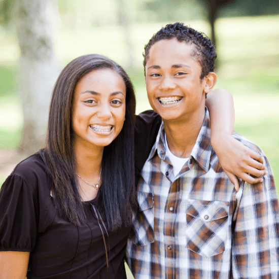 Two teens with traditional braces smiling