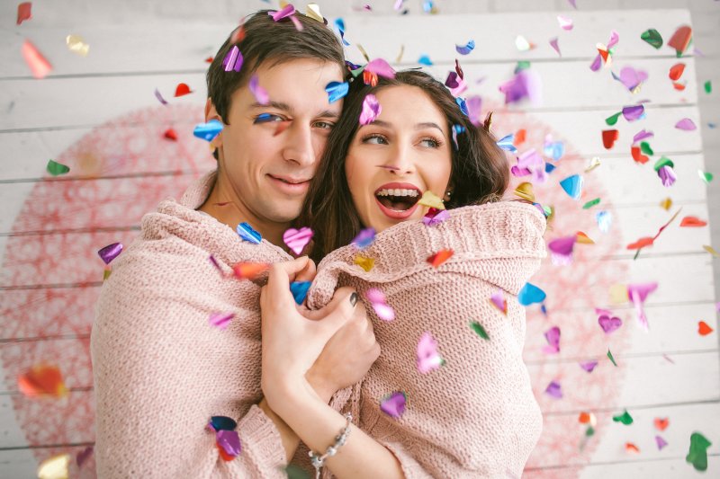 Couple with braces smiling and dancing in confetti