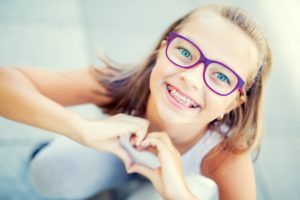 Young girl with braces making heart with her hands