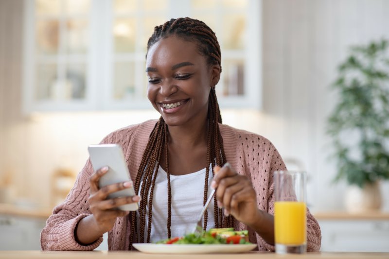 Woman with braces smiling while eating vitamin-rich lunch