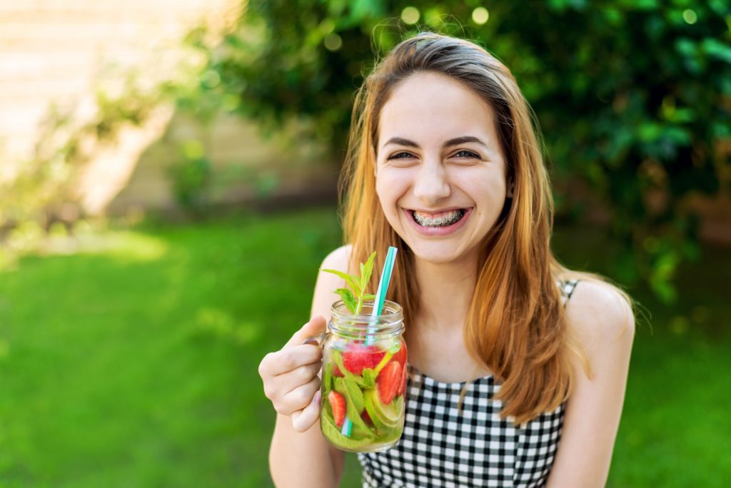 Woman with braces enjoying fruity drink outside