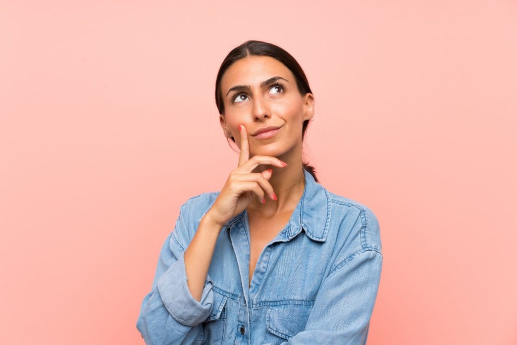 Woman in denim shirt thinking about Invisalign vs braces