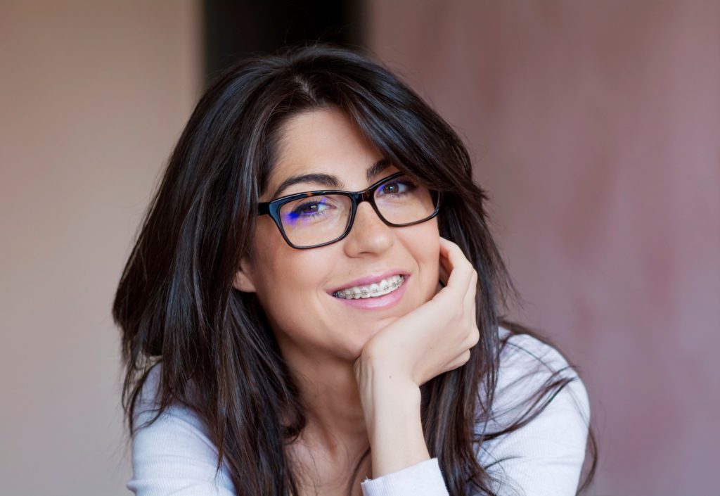 Woman with braces and glasses smiling