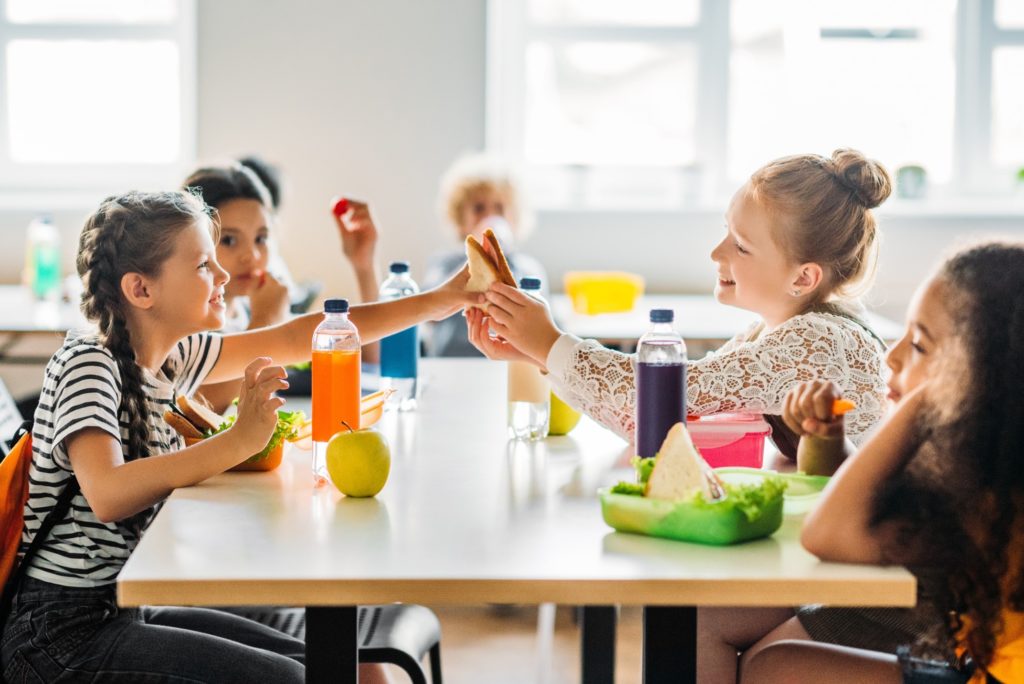 Young kids smiling while eating lunch together