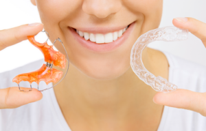 a person smiling and holding their retainer